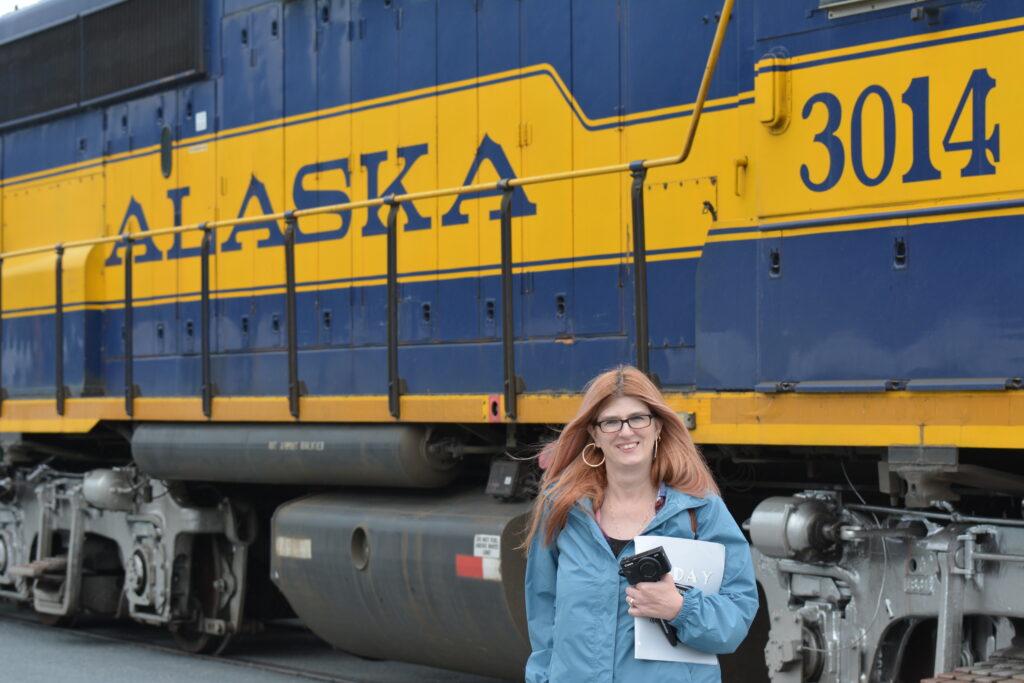 Woman standing in front of a train that says Alaska