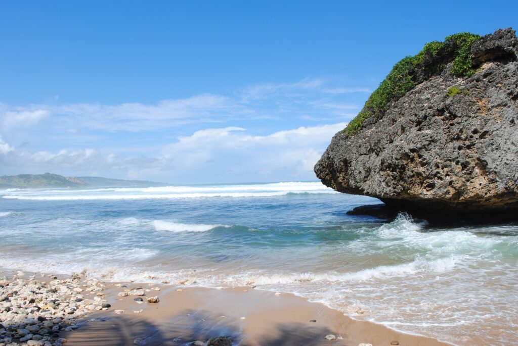 Beach with sand and a cliff blue water in Barbados